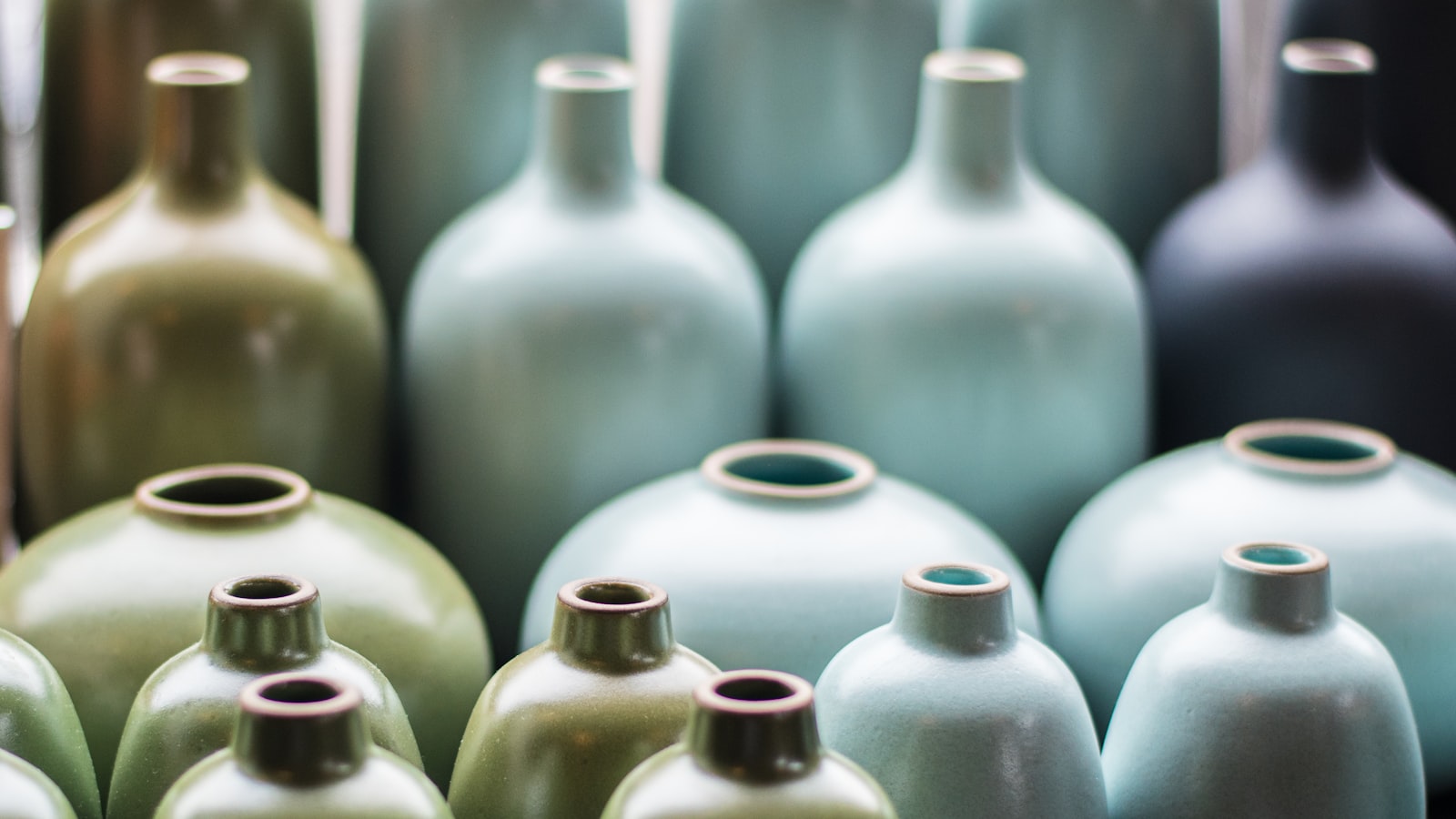 A grouping of soft-toned stoneware ceramic vessels in muted clay and cream tones.
