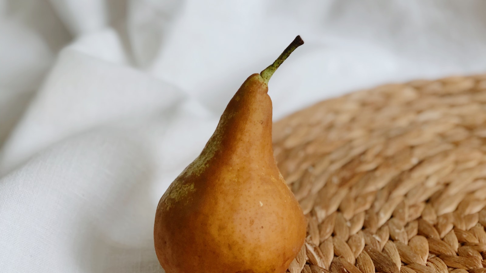 A single pear on woven linen.